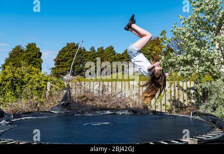 Camptoun, East Lothian, Schottland, Vereinigtes Königreich. April 2020. Eine Gemeinde im Lockdown: Bewohner einer kleinen ländlichen Gemeinde zeigen, wie das Leben im Lockdown für sie ist. Im Bild: Louisa im Alter von 11 Jahren in P7. Zu ihrer Hausschule gehören PE-Übungen auf einem Trampolin Stockfoto