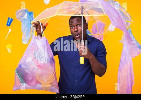 Problem der Papierkorb, Kunststoff Recycling, Umweltverschmutzung und ökologischen Konzept - überrascht Mann, der müllsack auf gelbem Hintergrund Stockfoto