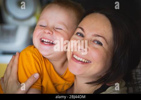 Glückliche Familie lachende Gesichter, Mutter hält liebenswert Kind Baby Junge, lächelnd und umarmend, nah Grenze, Schönheit des Lächelns, weiblich isoliert auf weiß Stockfoto