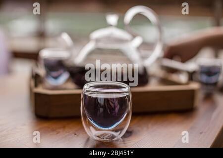 Der violette florale Kräutertee wird vom Brauer in die Tasse gegossen. Stockfoto