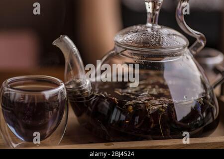 Der violette florale Kräutertee wird vom Brauer in die Tasse gegossen. Stockfoto