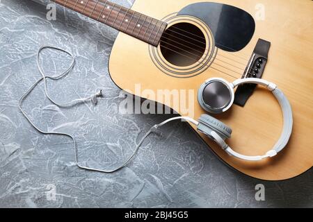 Klassische Gitarre und Kopfhörer auf grauem Hintergrund Stockfoto