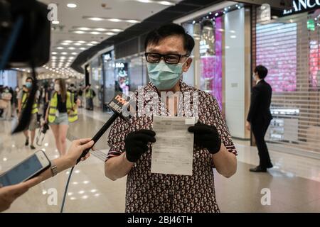 Hongkong, China. April 2020. Ein Mann, der eine chirurgische Maske und Handschuhe trägt, zeigt ein Strafzettel, das er im öffentlichen Raum erhalten hat, während er mit lokalen Medien im Hong Kong IFC Einkaufszentrum sprach. Die Polizei brach am Dienstagabend einen Protestversuch im luxuriösen IFC-Einkaufszentrum in Central ab. Beamte sperrten einen Teil des Atriums ab und mehrere Festgeld-Tickets wurden an Menschen ausgestellt, weil sie die sozialen Distanzierungsregeln missachten. Die Regeln verbieten öffentliche Versammlungen von mehr als vier Personen wegen der Covid-19-Pandemie. Quelle: SOPA Images Limited/Alamy Live News Stockfoto