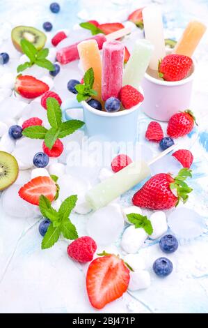 Hausgemachte Erdbeerpopsicles mit Eis, verschiedenen Beeren und Minze. Sommer gesundes Essen Konzept mit Kopierraum. Fruchteis mit verschiedenen Geschmacksrichtungen. Stockfoto