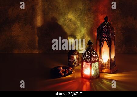 Festliche Grußkarte, Einladung zum muslimischen Feiertag Ramadan Kareem. Iftar Abendessen Hintergrund, dekorative arabische Laternen glühen in der Nacht, Tasse Tee, Stockfoto