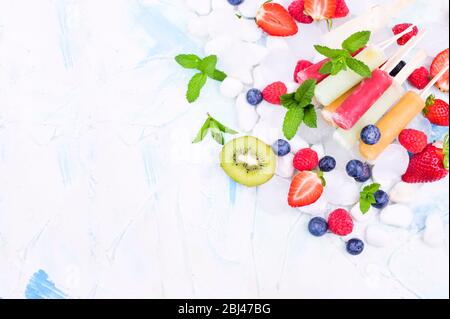 Hausgemachte Erdbeerpopsicles mit Eis, verschiedenen Beeren und Minze. Sommer gesundes Essen Konzept mit Kopierraum. Fruchteis mit verschiedenen Geschmacksrichtungen. Oben. Stockfoto