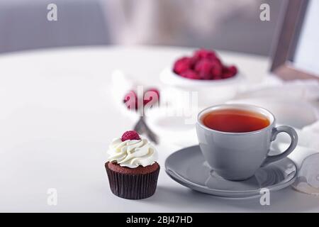 Schöner Schokoladenkuchen mit Himbeere und Tasse Tee, auf dem Tisch Stockfoto