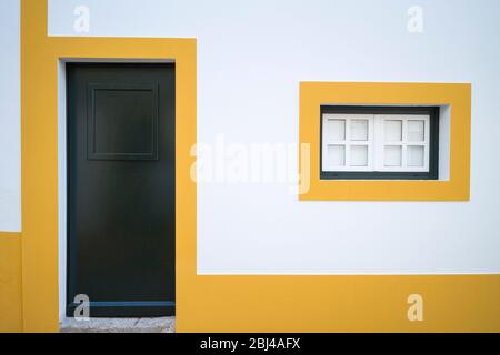 Typische Farben von Evora - weiß und gelb geometrische Box Haus mit dunkelgrünen Eingangstür in der Straße in Evora, Portugal Stockfoto