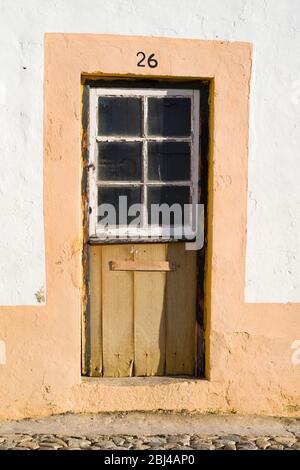 Typisches malerisches Haus mit alter Eingangstür in einer gepflasterten Steinstraße in Evora, Portugal Stockfoto