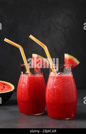 Smoothies mit Wassermelone in zwei Gläsern auf dunklem Hintergrund, Vertikal-Format Stockfoto