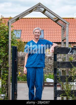 Camptoun, East Lothian, Schottland, Vereinigtes Königreich. April 2020. Eine Gemeinde im Lockdown: Bewohner einer kleinen ländlichen Gemeinde zeigen, wie das Leben im Lockdown für sie ist. Raphi ist eine NHS Krankenschwester, die derzeit am Royal Infirmary of Edinburgh lebt und weiterhin zur Arbeit geht. Sie zog vor kurzem ins Dorf und hat viel in ihrem Garten gearbeitet, wenn sie aus dem Dienst war Stockfoto