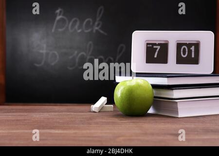 Apfel, Bücher und Uhr auf Schreibtisch Hintergrund Stockfoto