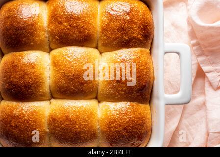 Ziehen Sie Brötchen mit Sauerteig und Weißmehl hausgemacht auseinander. Leckere Brötchen mit goldener Kruste in einem Keramiktablett Stockfoto