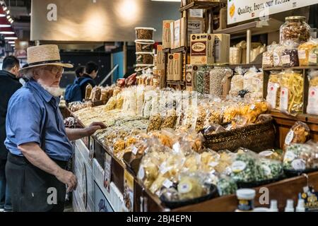 Amish Verkäufer kümmert sich um seinen Laden am Reading Terminal Market. Stockfoto