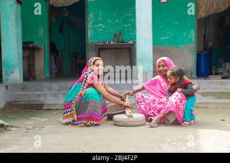 Indische Frau hält ein Kind und mahlen Mehl in einem Dorf Stockfoto