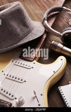 E-Gitarre mit Kopfhörer, Hut und Mikrofon auf Holzhintergrund Stockfoto