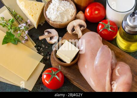 Das Essen Hintergrund italienisch. Zutaten für das Kochen Lasagne mit Huhn und Pilzen auf einem dunklen Steingrund. Stockfoto