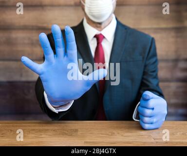 Ein Arzt oder Geschäftsmann trägt psa blaue Handschuhe und Gesichtsmaske während der Coronavirus Pandemie gestikuliert Menschen, weg und soziale Distanz zu bleiben, wenn p Stockfoto