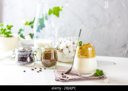 Glas mit Wassertropfen Kaffee Trend - Dalgona Kaffee, Schlagsahne Instant-Kaffee und Zutaten auf hellen rustikalen Hintergrund, Kopierer Raum. Stockfoto