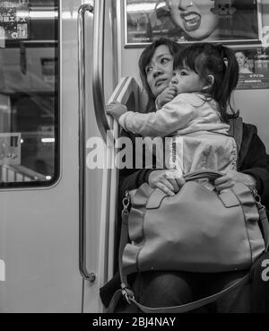 Eine Mutter und ihr kleines Kleinkind nehmen eine Zugfahrt zurück nach Hause, Tokio Japan. Stockfoto