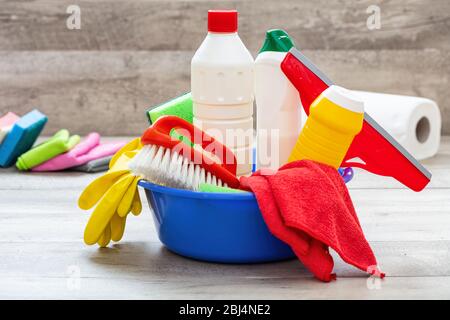 Reinigungsmittel auf dem Boden, Innenhintergrund. Chemische Waschmittelflaschen in einer blauen Schüssel. Hausrat- oder betriebswirtschaftliche Sanitäranlagen Stockfoto