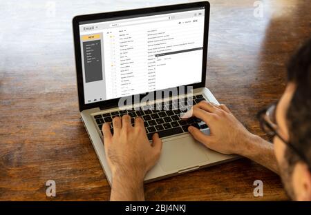 E-Mail Posteingang Nachrichtenliste auf einem Computer-Bildschirm, Mann mit einem Laptop, hölzernen Büroschreibtisch Hintergrund, Geschäft Home Office Konzept. E-Mail-Adresse Stockfoto