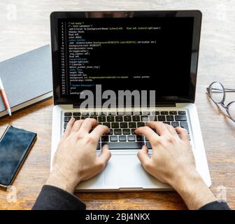 Computercode, Softwarekonzept. Programmierer, die mit einem Laptop arbeiten, Programmiercode auf dem Bildschirm, Bürohintergrund. Entwicklung von Codierungstechnologien. Stockfoto