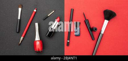 Kosmetikzubehör in rot und schwarz aufmachen. Lippenstift, nagelpoliermittel, Augenstift und Bürsten vor rotem und schwarzem Farbhintergrund Stockfoto