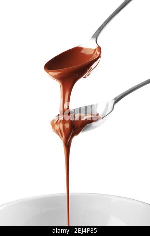 Geschmolzene Milchschokolade, die aus Löffeln, isoliert auf weiß, gegossen wird Stockfoto
