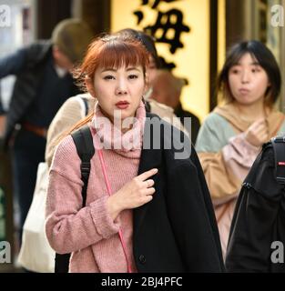 Eine Frau, die auf der Haupteinkaufsstraße der Insel Enoshima in Japan spazieren geht. Stockfoto