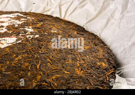 Chinesisch gepresster PU-erh Tee auf Geschenkpapier, Nahaufnahme Stockfoto