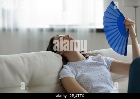 Unwell junge Frau entspannen winken mit Handventilator Stockfoto