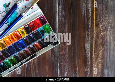 Set von Aquarellfarben und Pinsel für die Malerei Nahaufnahme auf Holztisch. Kopierplatz flach legen. Stockfoto