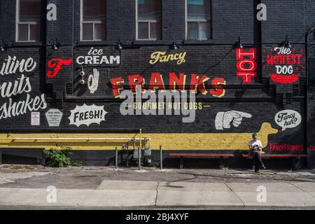 Frau, die sich an der Seite des berühmten Franks Hotdog Restaurants in Toronto in Kanada befindet. Stockfoto