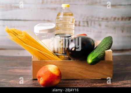 Lebensmittel. Krise Lebensmittel Box Lager für Coronavirus Quarantäne Isolationszeit in Holz Hintergrund. Verschiedene Lebensmittel in Aluminiumdosen, Reis, Nudeln, Öl Stockfoto