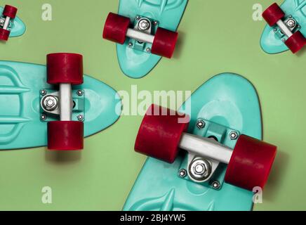 Turquoise Skateboards auf grünem Hintergrund, Draufsicht. Konzept des Sports Lifestyle, Kultur, Freizeit, Hobby, alternative Verkehrsmittel Stockfoto