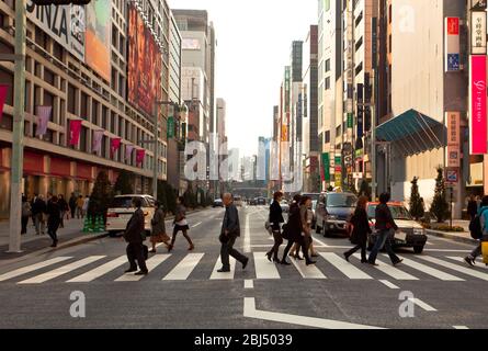 Menschen an einer geschäftigen Kreuzung im Ginza-Viertel von Tokio in Japan mit modernen Gebäuden im Hintergrund. Stockfoto