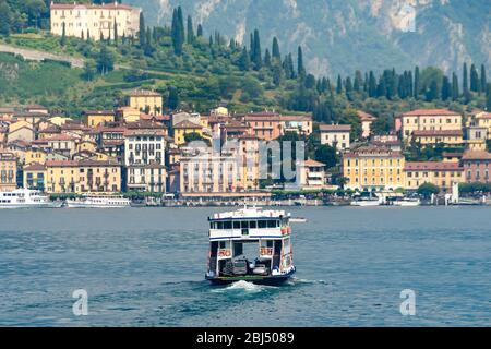 CADENABBIA, COMER SEE - JUNI 2019: Autofähre über den Comer See nach Bellagio, das im Hintergrund ist. Stockfoto