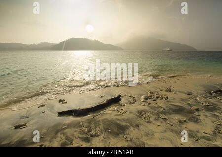 Driftwood an einem Papua-Neuguinea-Strand mit entfernten Inseln. Stockfoto