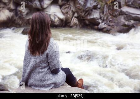 Fotografie von Frau in der Nähe von schönen Wasserfall auf Felsen Stockfoto