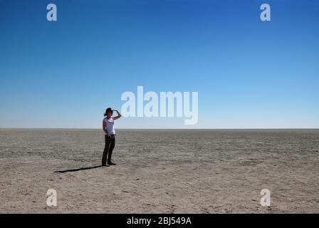 Frau, die in die Ferne schaut auf Etosha PAN, Namibia, Afrika. Stockfoto