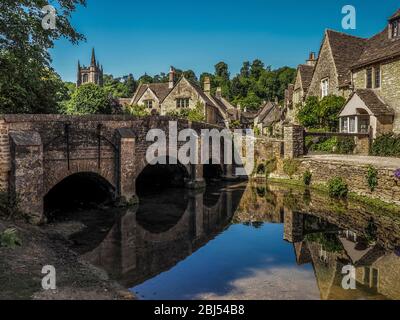 Eine Steinbrücke über einen sanften Bach führt den Weg in das Dorf Castle Combe in England. Stockfoto