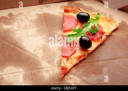 Pepperoni-Pizza mit Rucola und Oliven auf Karton Stockfoto
