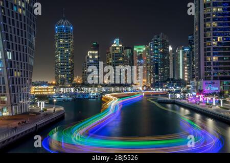 Durch die Dubai Marina kreisen Lichtspuren von arabischen Daus. Stockfoto