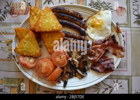 Ein komplettes englisches Frühstück in Großbritannien und Irland, das Speck Würstchen Eier schwarzen Pudding gebackene Bohnen Tomaten Pilze Getränke Kaffee oder Tee umfasst Stockfoto