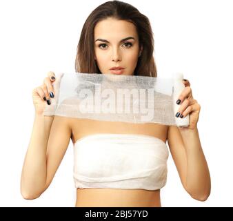 Junge schöne Frau mit einem Verband auf der Brust, hält Gaze, isoliert auf weiß Stockfoto