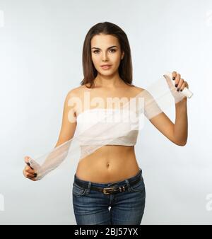 Junge schöne Frau mit einem Verband auf der Brust, hält Gaze, isoliert auf weiß Stockfoto