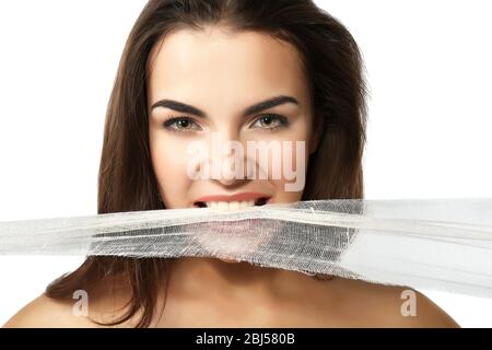 Junge schöne Frau zerreißt Gaze mit ihren Zähnen, isoliert auf weiß Stockfoto