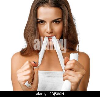 Junge schöne Frau zerreißt Gaze mit ihren Zähnen, isoliert auf weiß Stockfoto