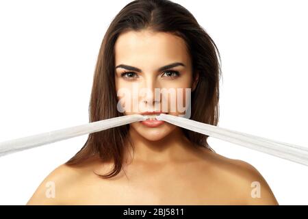 Junge schöne Frau zerreißt Gaze mit ihren Zähnen, isoliert auf weiß Stockfoto